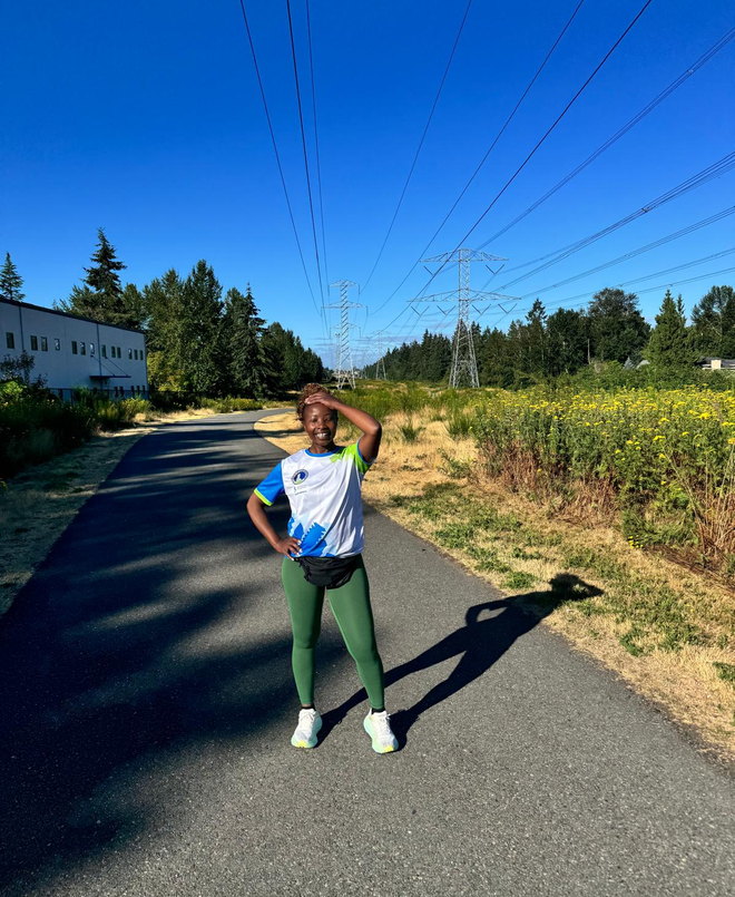 On a walking trail on a bright morning, hand raised against the sun