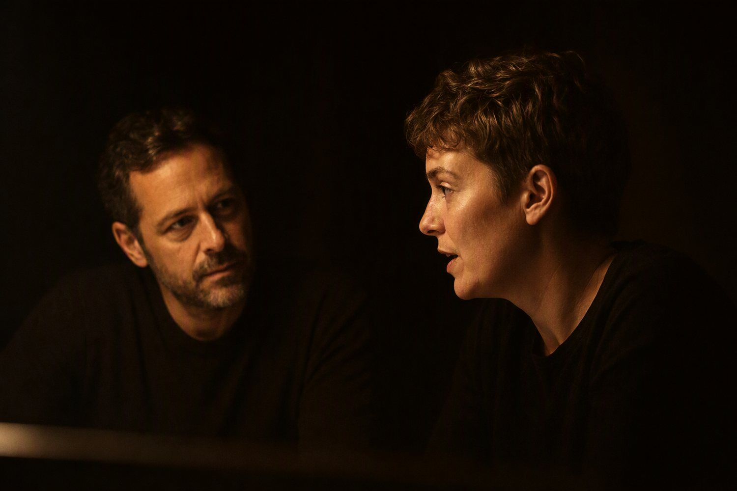 Two people working across a dark table late at night, planning an event.