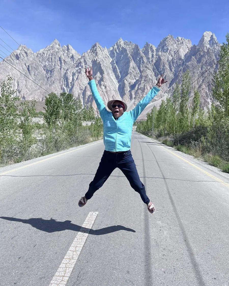 Maria Kamau jumping for joy on a mountain road in northern Pakistan
